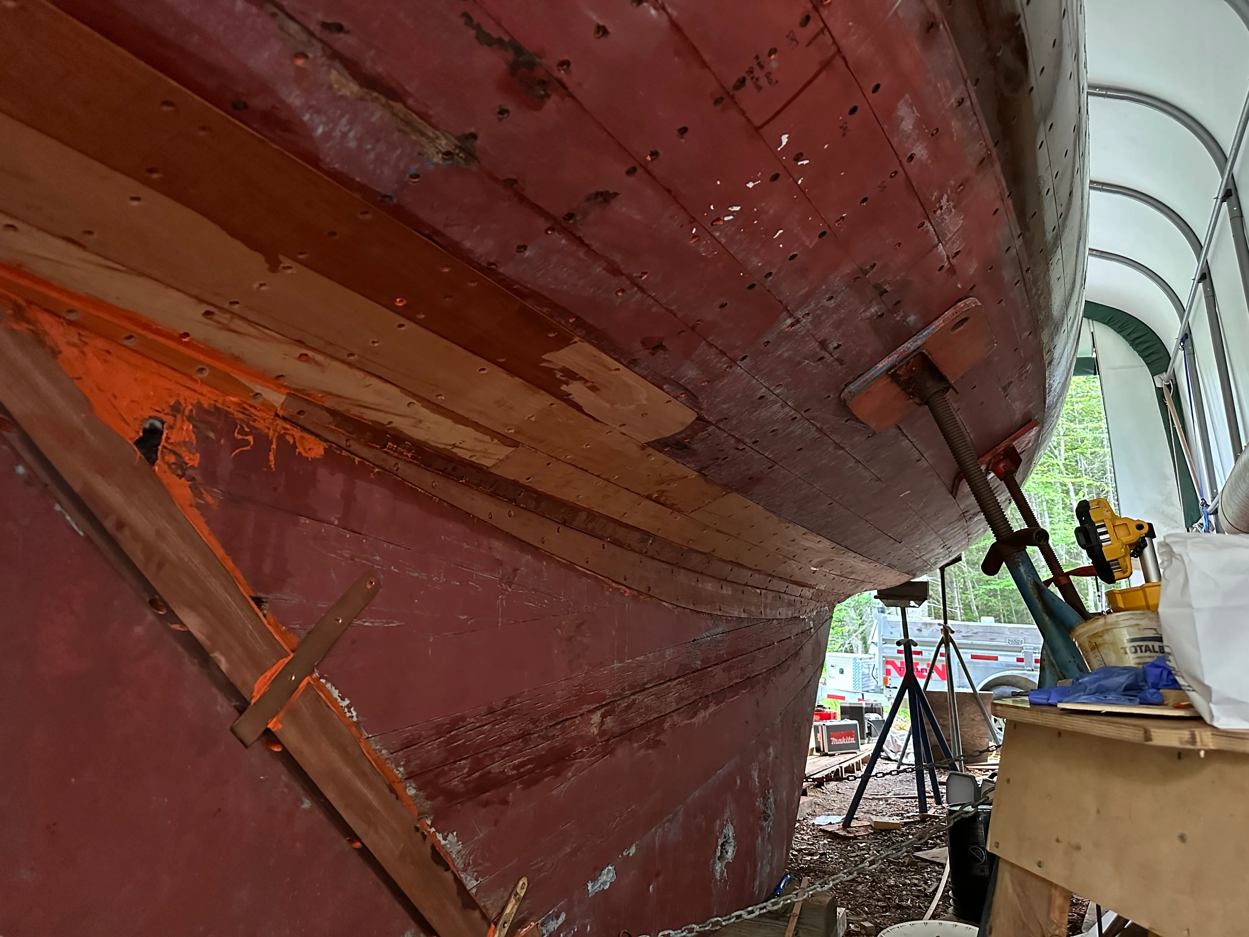 Completed stern view showing new planking with red lead visible at the tuck