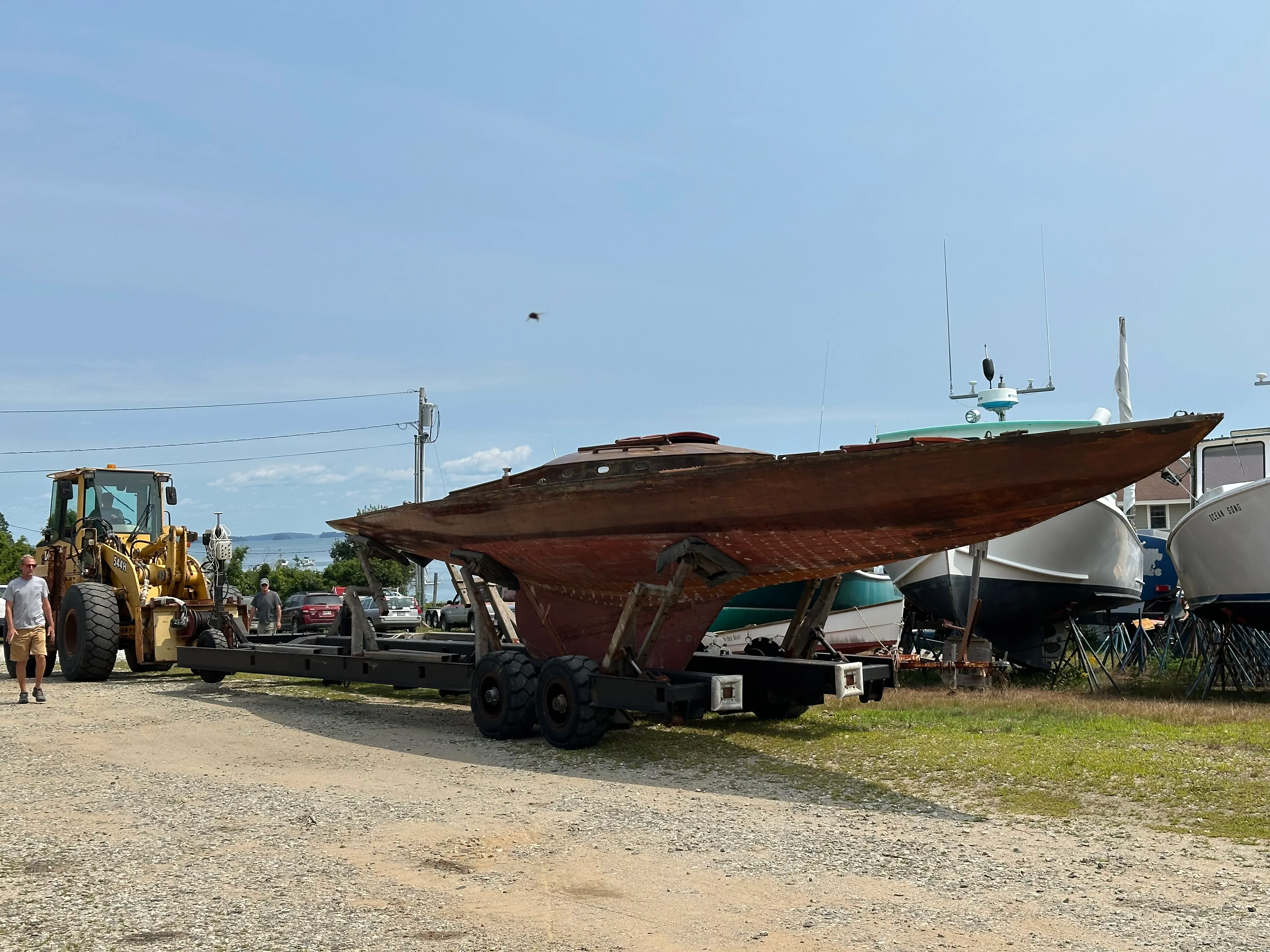Close-up broadside of the sailboat on the trailer at the boatyard, showing the full hull profile