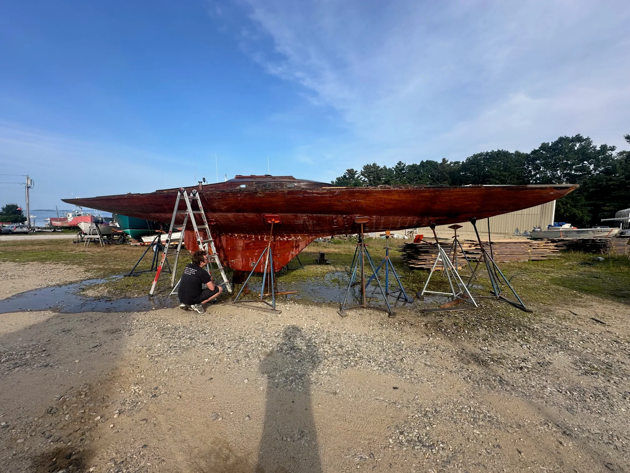 Person sitting under the boat on stands while water runs over the hull