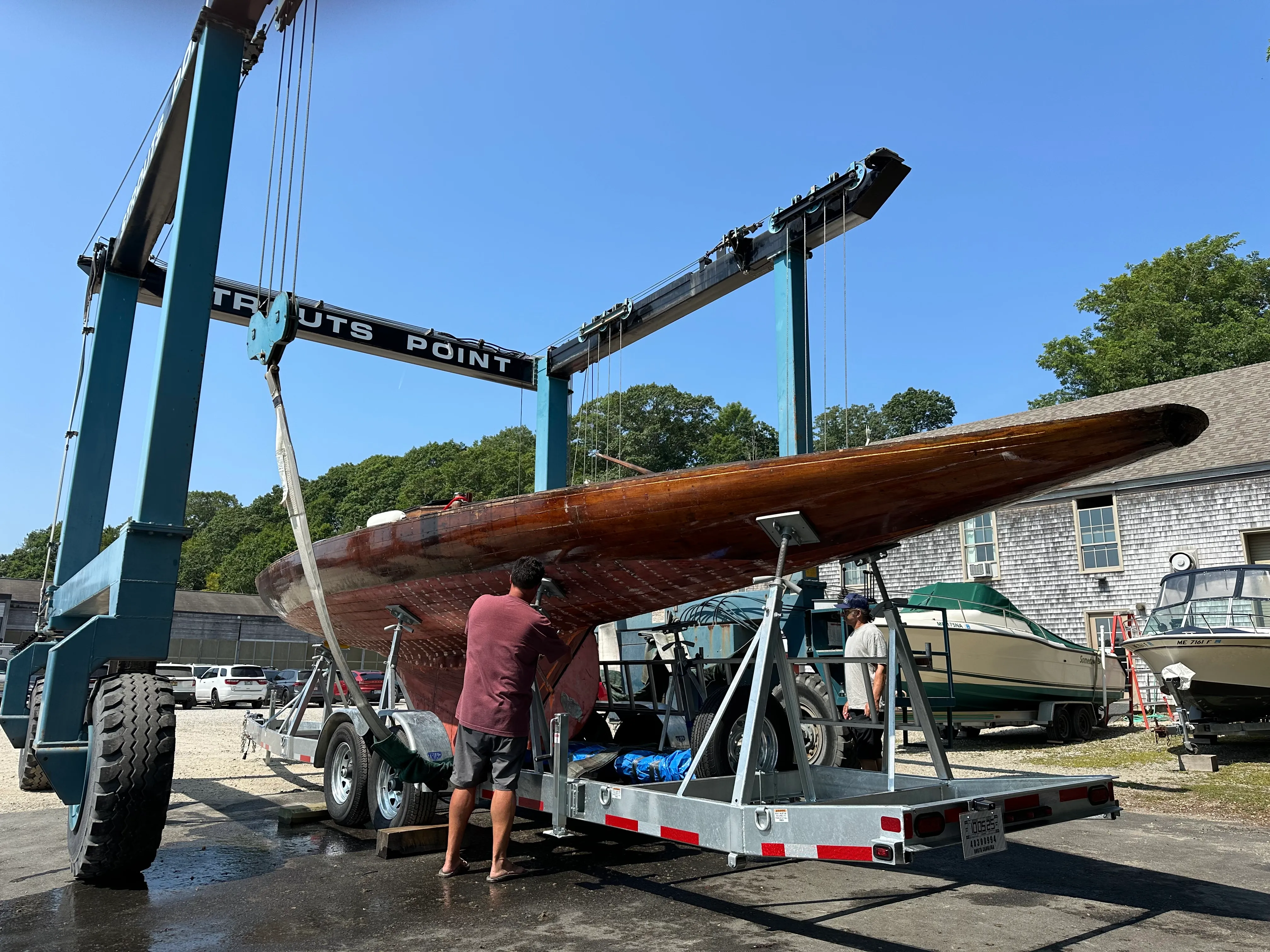 The Travelift lowering the sailboat onto a flatbed trailer at the boatyard