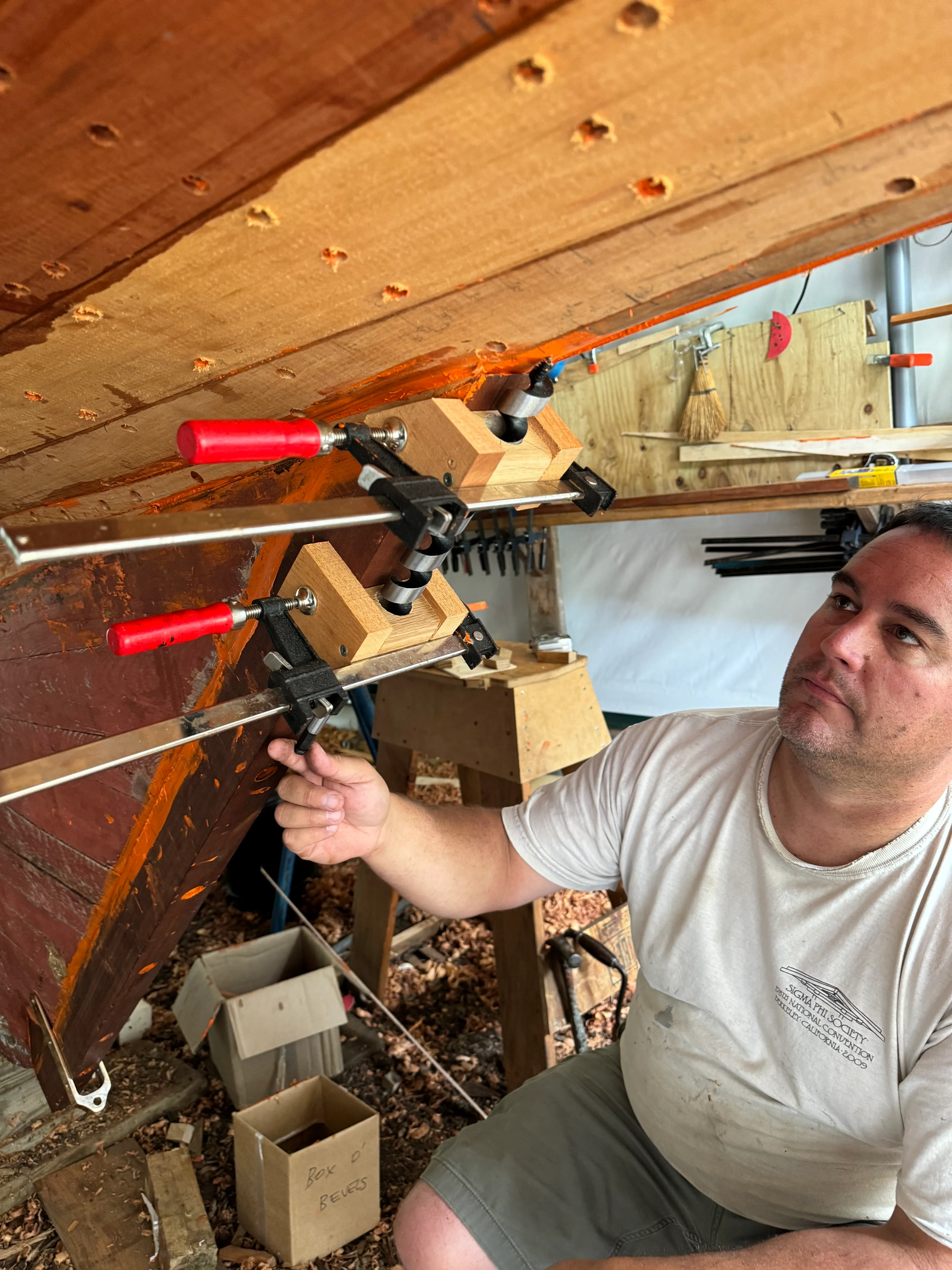 Person using a drilling jig clamped to the sternpost to bore the rudder port hole