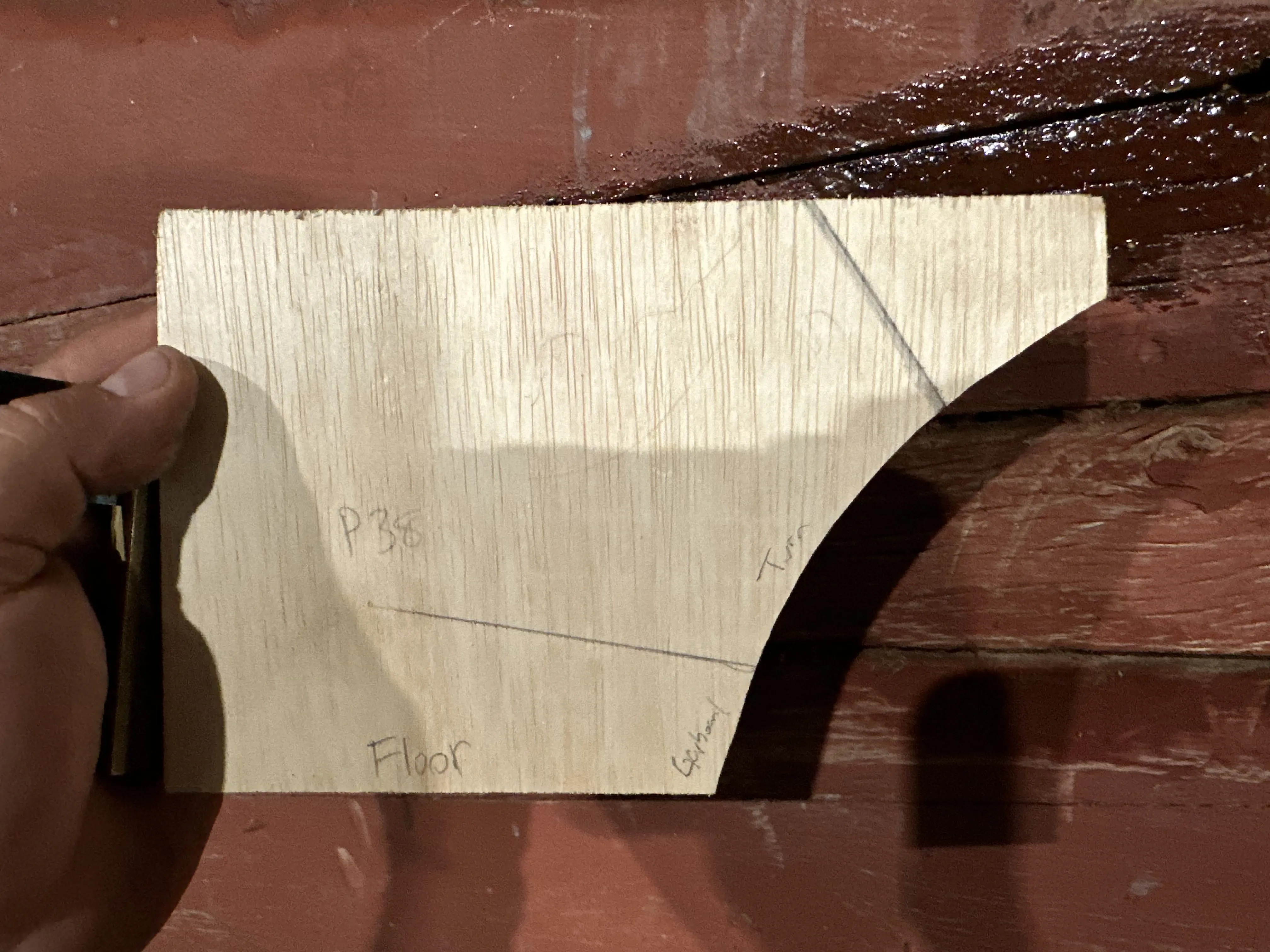 Cross-section template held against hull showing floor timber camber profile