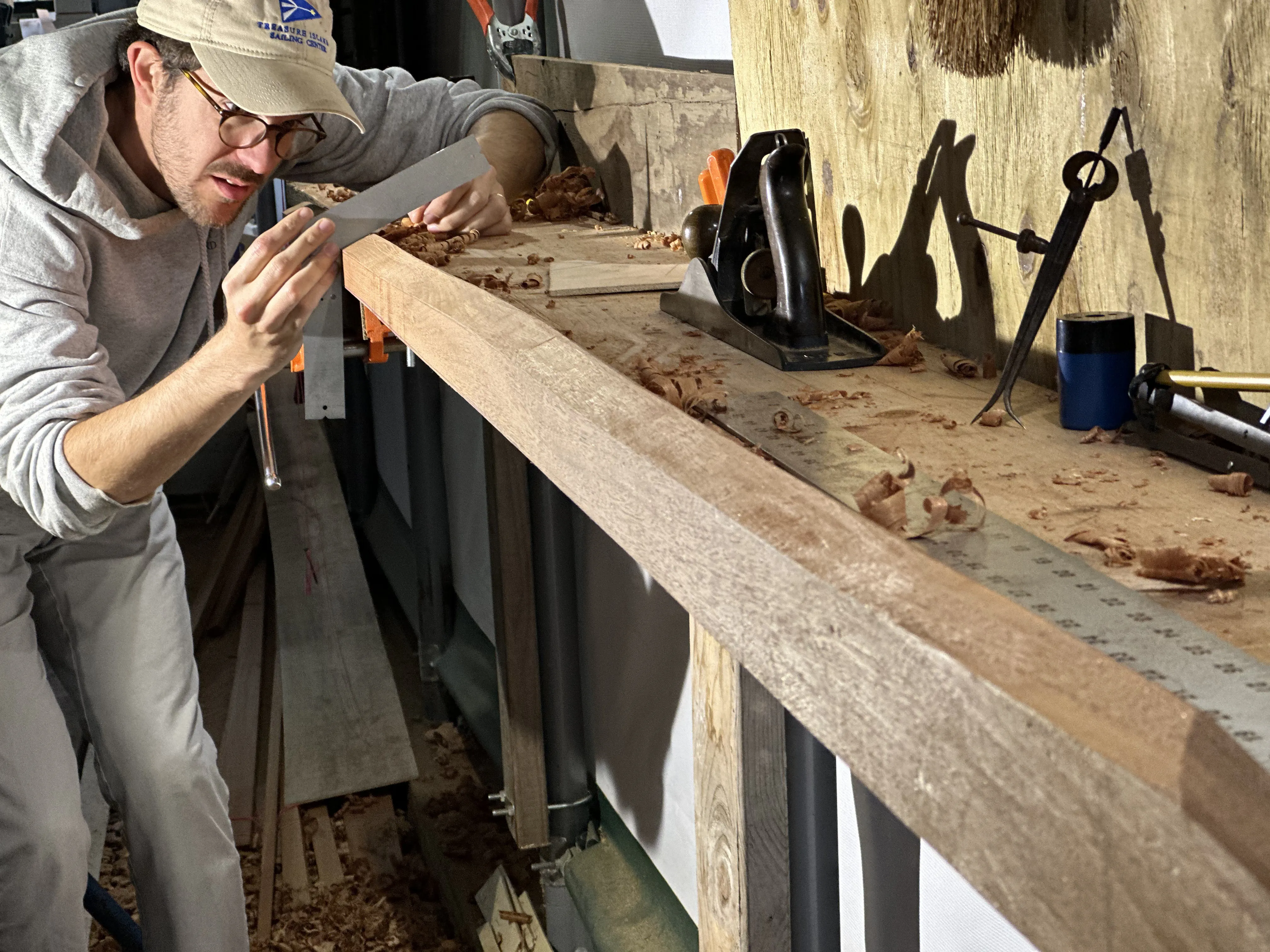 Person sighting down the edge of a plank on the workbench to check the bevel